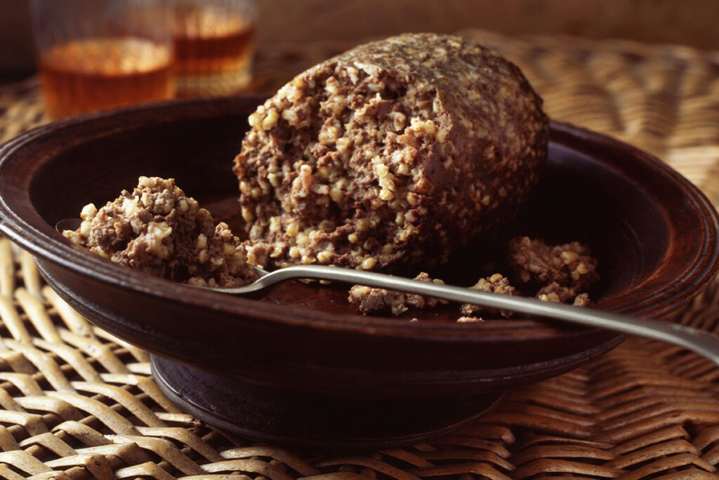 10 Platos Imprescindibles de Escocia para degustar 1 Haggis en cuenco sobre mantel individual de mimbre con vasos de whisky